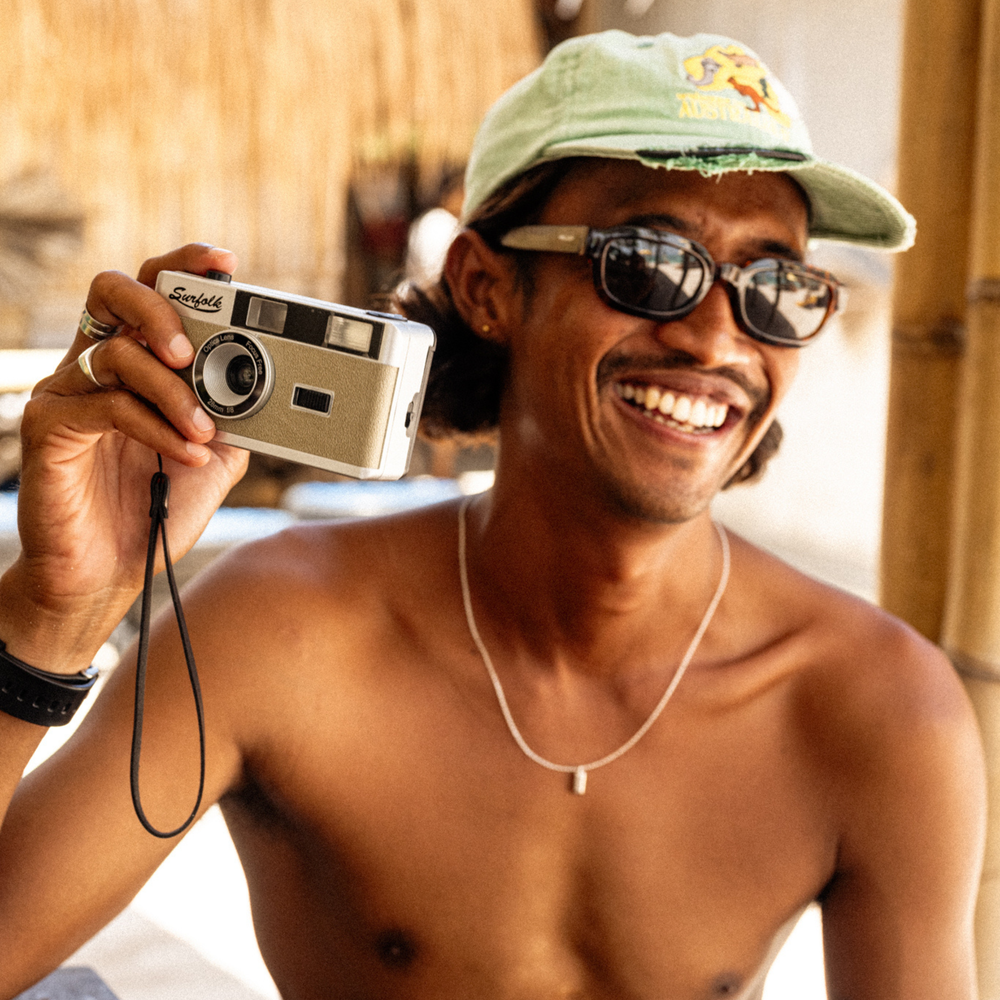 Man holding a film camera with a bamboo background
