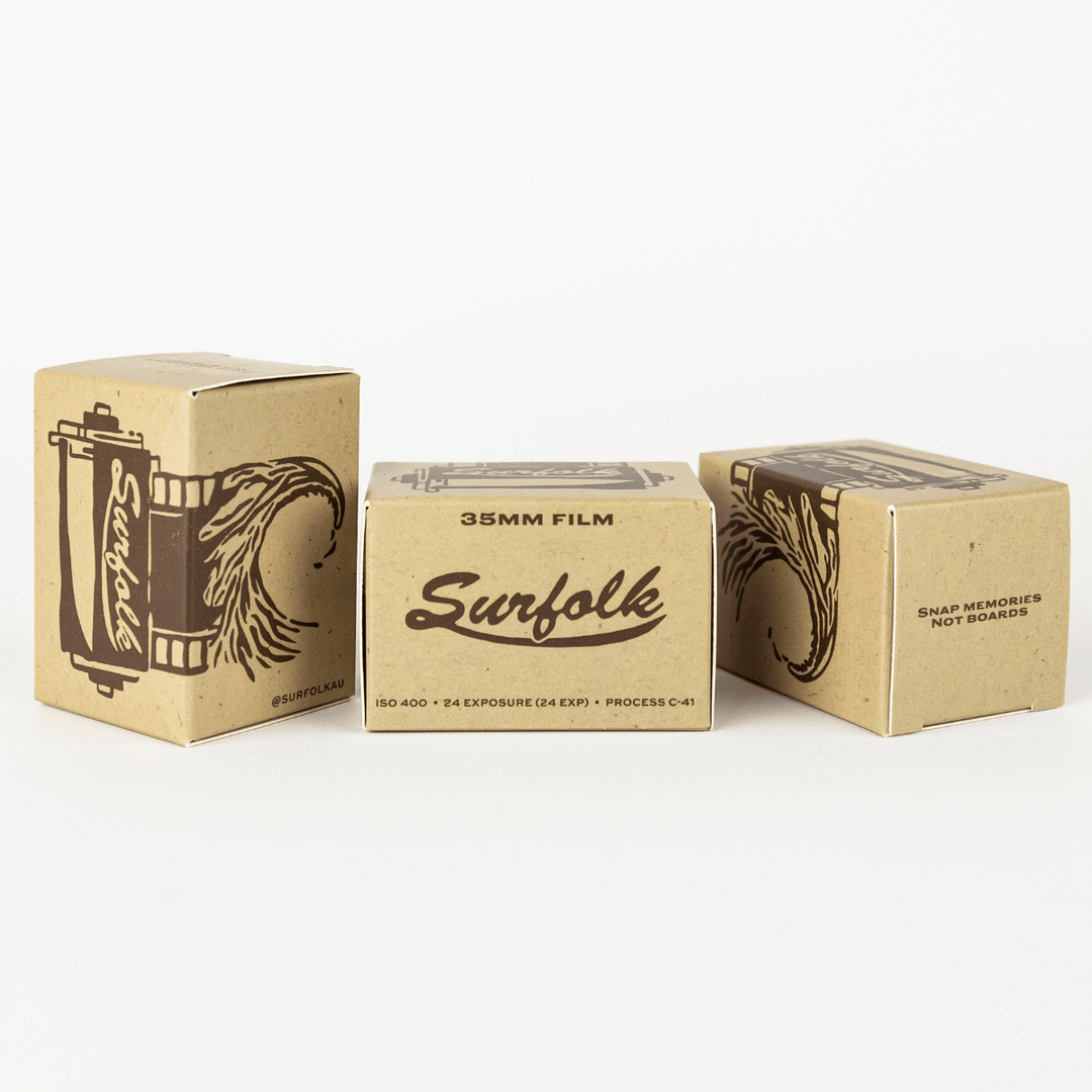 Three brown cardboard boxes labeled 'Surfolk 35mm Film' arranged in a triangular formation, with the branding and film details visible.