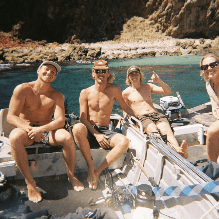 A 35mm film image of Four people on a boat in a rocky coastal area.