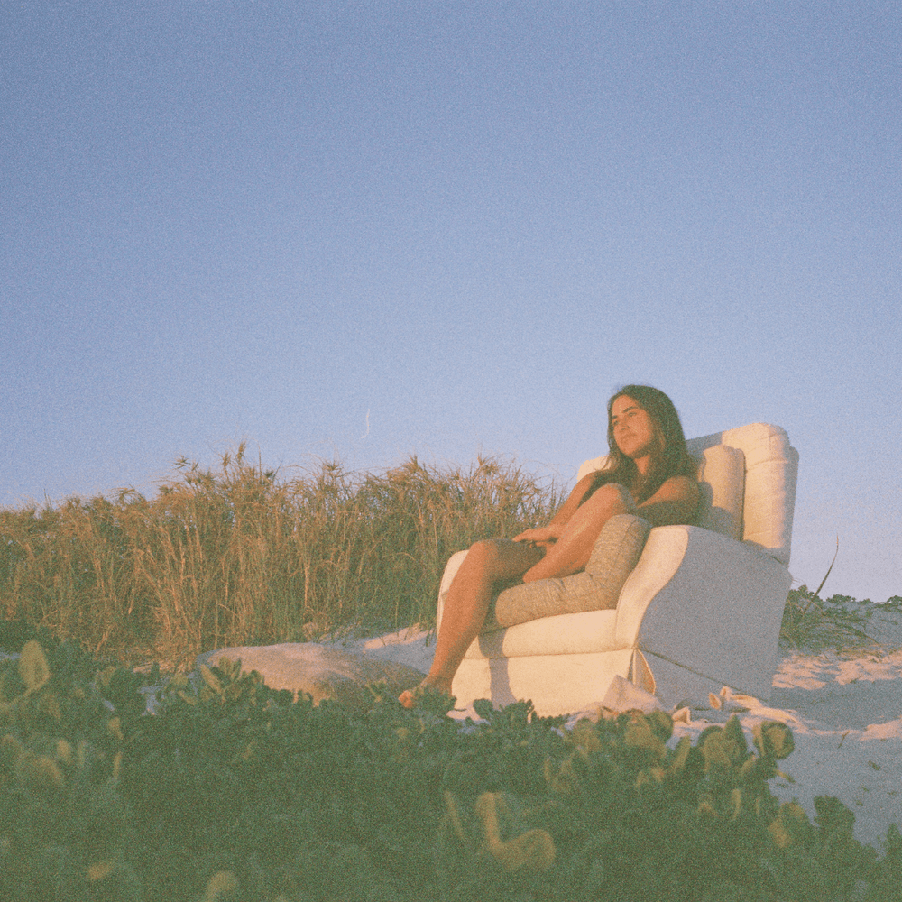 A 35mm film image of a Person sitting in a chair on a beach with clear sky.