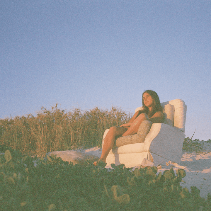 A 35mm film image of a Person sitting in a chair on a beach with clear sky.