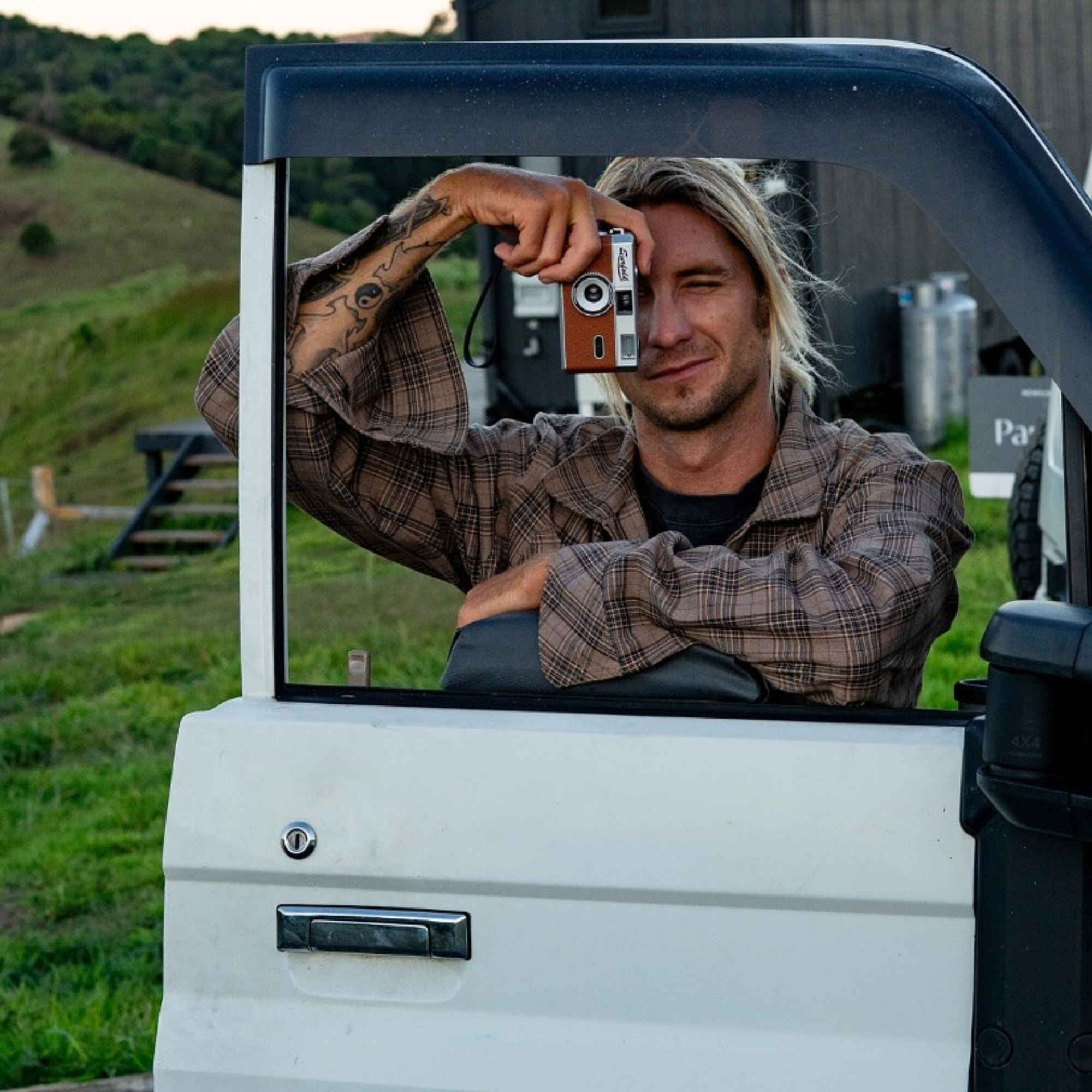 Man taking a photo on a film camera in a vehicle with a scenic background